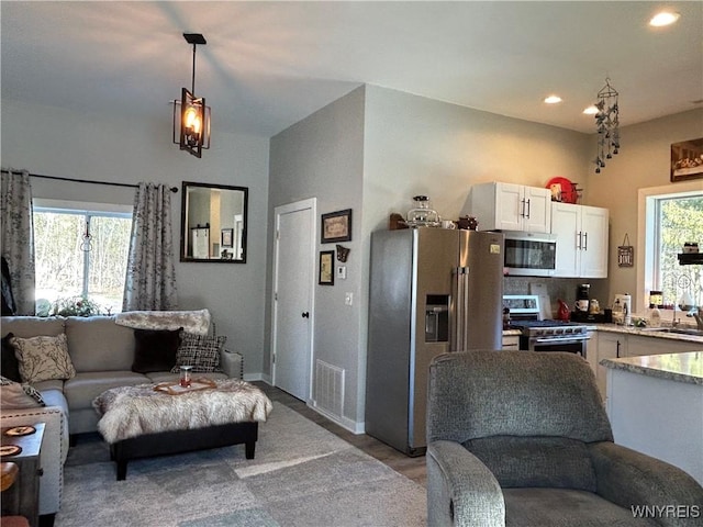 kitchen featuring stainless steel appliances, plenty of natural light, open floor plan, and white cabinets