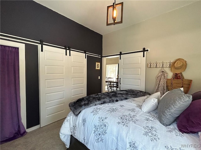 bedroom featuring a barn door, carpet, and a closet