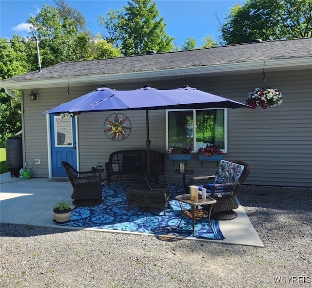 rear view of house featuring a shingled roof, outdoor lounge area, and a patio