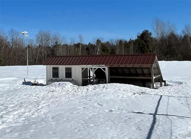 snow covered structure with an outdoor structure and a forest view