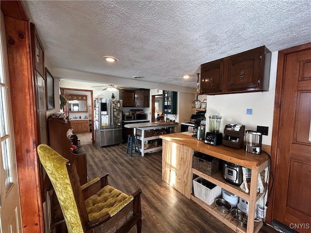 kitchen featuring a ceiling fan, freestanding refrigerator, dark wood-type flooring, dark brown cabinets, and a textured ceiling