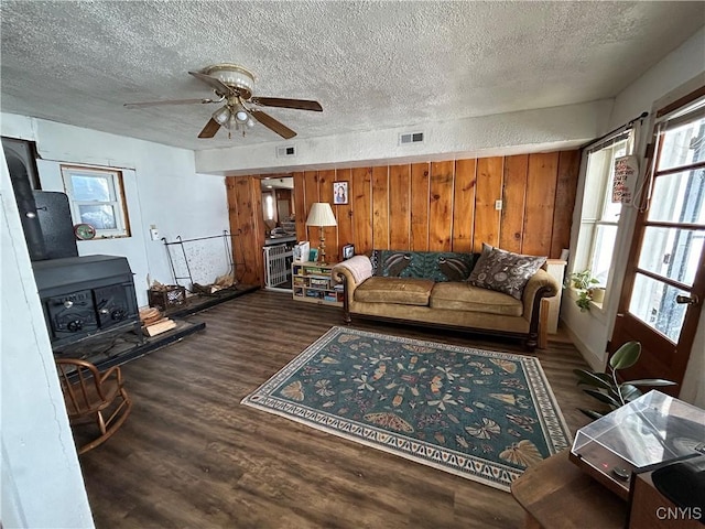 living area featuring visible vents, wood finished floors, and a wood stove