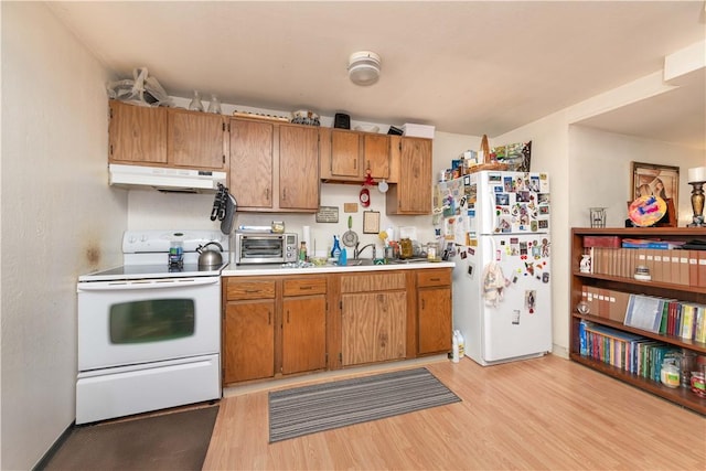 kitchen featuring white appliances, light wood-style floors, under cabinet range hood, and light countertops