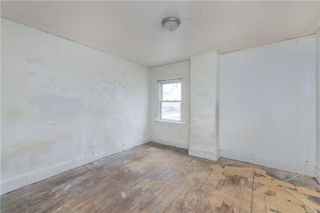 spare room with baseboards and hardwood / wood-style floors