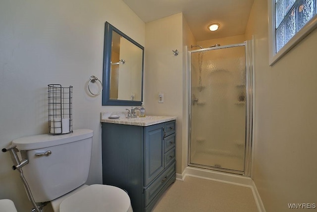 bathroom with a shower stall, toilet, vanity, and baseboards