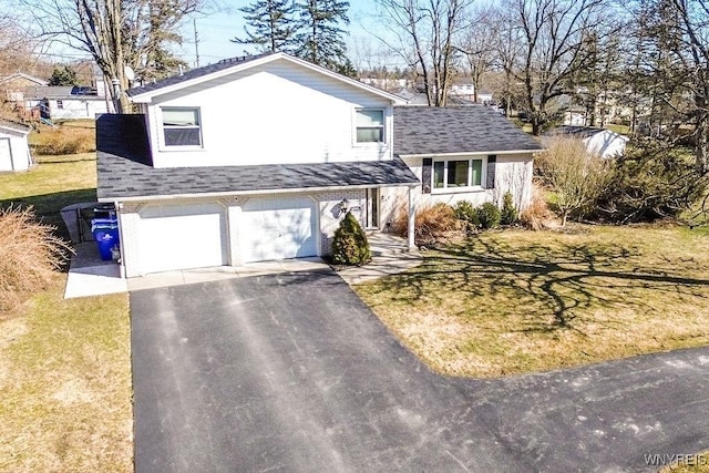 split level home featuring a front lawn, aphalt driveway, a shingled roof, a garage, and brick siding