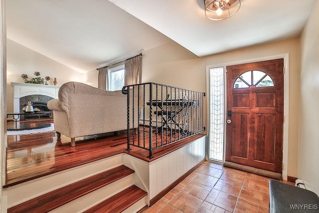 foyer with baseboards, lofted ceiling, and a tiled fireplace