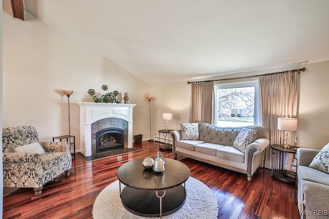 living room featuring baseboards, lofted ceiling, hardwood / wood-style floors, and a tiled fireplace