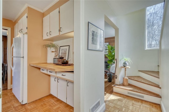 kitchen with visible vents, white cabinets, crown molding, and freestanding refrigerator