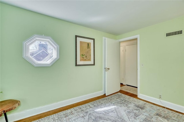 bedroom with wood finished floors, baseboards, and visible vents