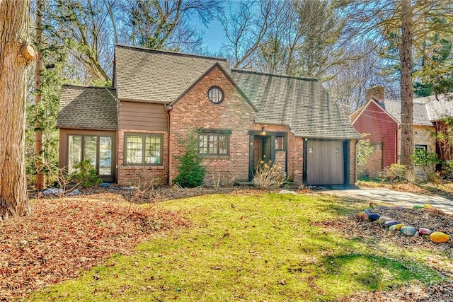 view of front facade with brick siding, a front lawn, and roof with shingles