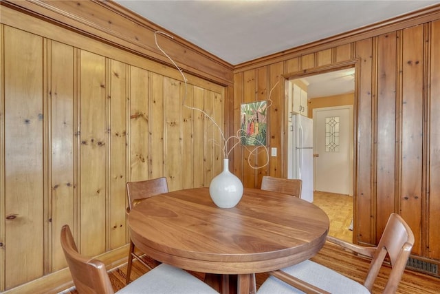 dining area featuring wooden walls and light wood-style floors