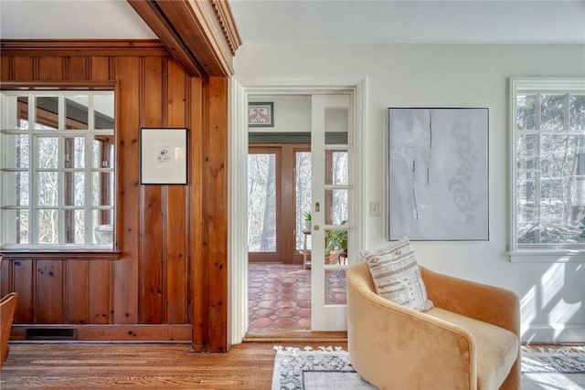 doorway to outside featuring wooden walls, wood finished floors, visible vents, and french doors