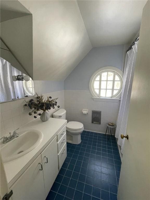 full bath featuring vanity, lofted ceiling, tile walls, toilet, and tile patterned floors