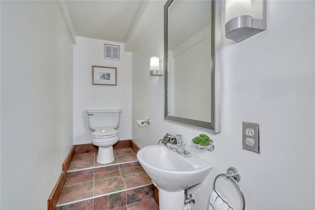 bathroom featuring toilet, baseboards, visible vents, and a sink