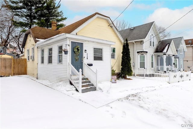 snow covered property featuring cooling unit, a chimney, and fence