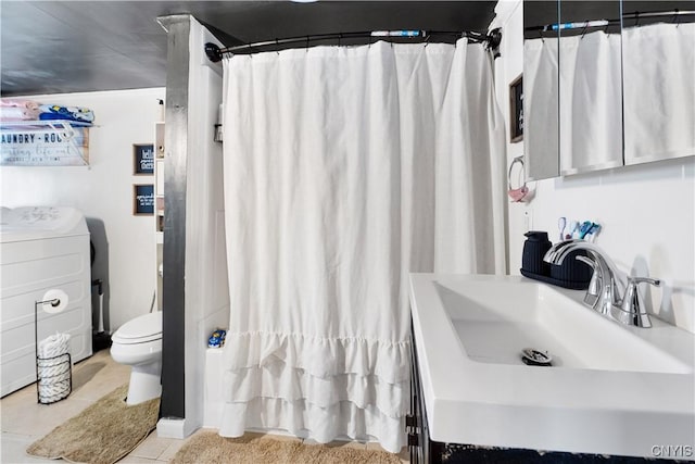 full bath featuring curtained shower, toilet, washer / dryer, tile patterned floors, and vanity