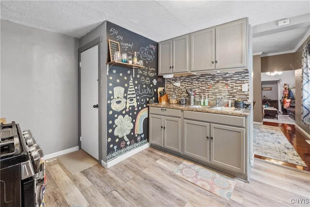 kitchen featuring gray cabinetry, baseboards, light wood-style floors, a textured ceiling, and a sink