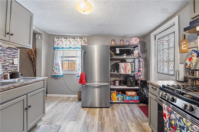 kitchen featuring backsplash, light wood-style flooring, gray cabinets, and freestanding refrigerator