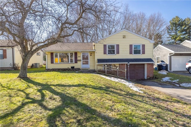 tri-level home featuring a front yard, central AC unit, brick siding, and aphalt driveway