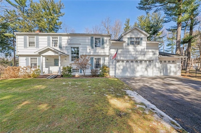 split foyer home featuring aphalt driveway, a garage, and a front lawn