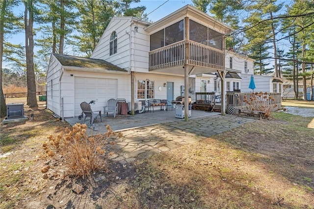 back of property with a sunroom, an attached garage, and a patio area