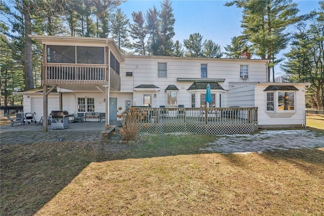 rear view of property with a sunroom, a chimney, a garage, a yard, and a patio area