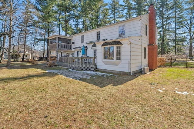 back of property featuring central air condition unit, a deck, a yard, a sunroom, and a chimney