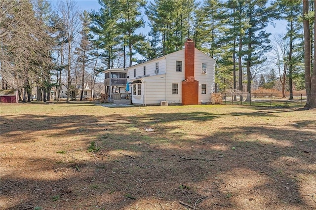 view of property exterior with a chimney, a yard, and fence