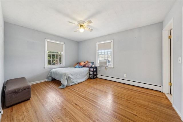 bedroom with a baseboard heating unit, baseboards, wood finished floors, and a ceiling fan