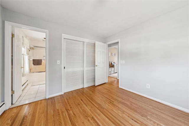 unfurnished bedroom featuring ensuite bathroom, baseboards, light wood-type flooring, and a closet