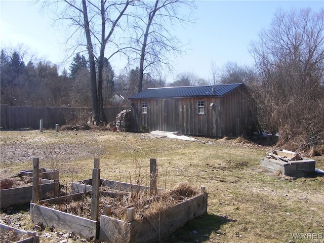 view of yard with an outbuilding, a vegetable garden, and fence