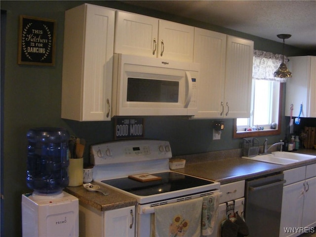 kitchen with hanging light fixtures, white appliances, white cabinetry, and a sink