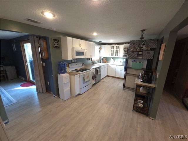 kitchen with light wood finished floors, visible vents, white appliances, white cabinetry, and a sink