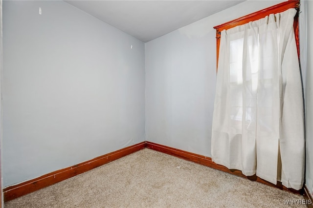 carpeted empty room featuring baseboards