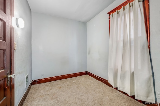 carpeted spare room with visible vents and baseboards