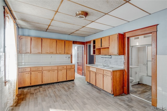 kitchen with open shelves, light wood-type flooring, light countertops, and a sink