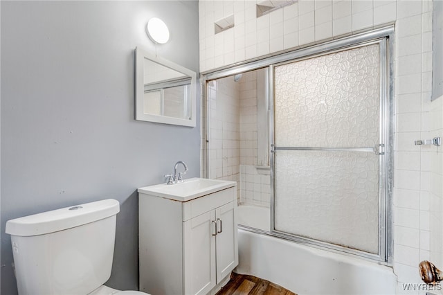 full bathroom with vanity, toilet, wood finished floors, and enclosed tub / shower combo