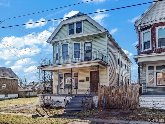 view of front of house with a porch, a balcony, and fence