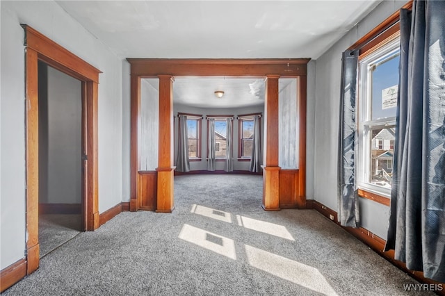 empty room with carpet, baseboards, and ornate columns