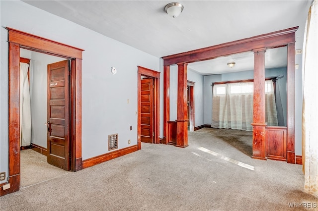 unfurnished room featuring carpet flooring, baseboards, visible vents, and decorative columns