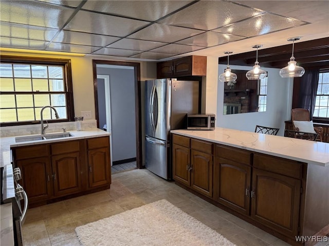 kitchen with a peninsula, pendant lighting, appliances with stainless steel finishes, and a sink