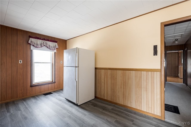 kitchen with wooden walls, visible vents, a wainscoted wall, freestanding refrigerator, and wood finished floors