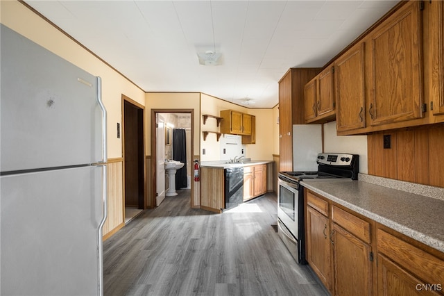 kitchen with black dishwasher, stainless steel range with electric cooktop, freestanding refrigerator, brown cabinetry, and dark wood-style flooring