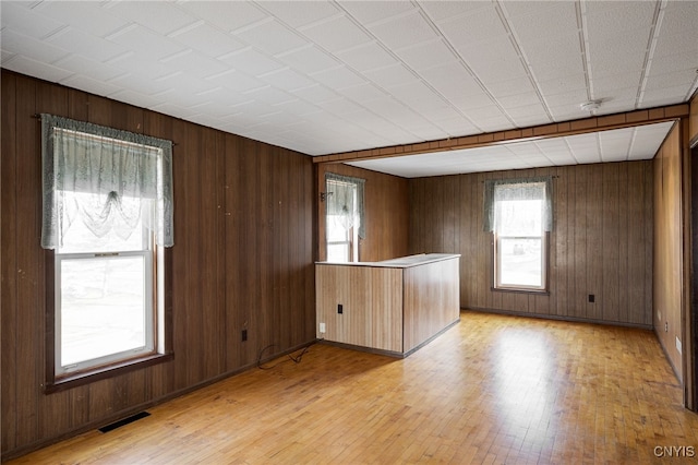 spare room with visible vents, light wood-style flooring, and wood walls