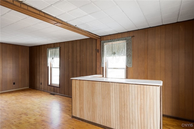 kitchen featuring light wood finished floors, visible vents, baseboards, and wooden walls