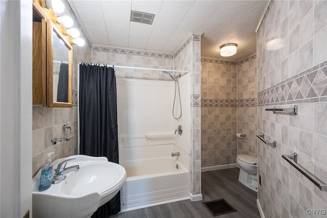 full bathroom with visible vents, toilet, tile walls, and a sink