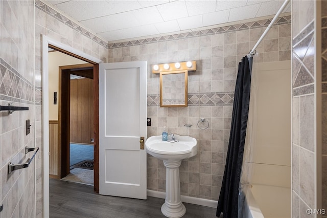 bathroom featuring tile walls, shower / bath combo with shower curtain, and wood finished floors