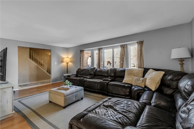 living area with light wood finished floors, stairway, and baseboards