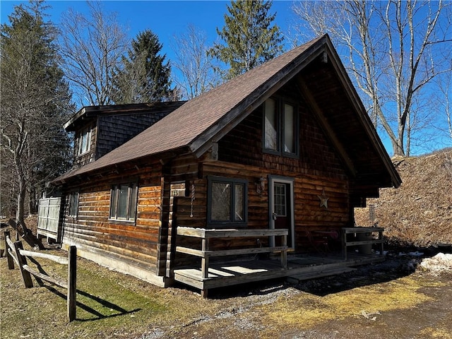 log cabin featuring log siding and a shingled roof